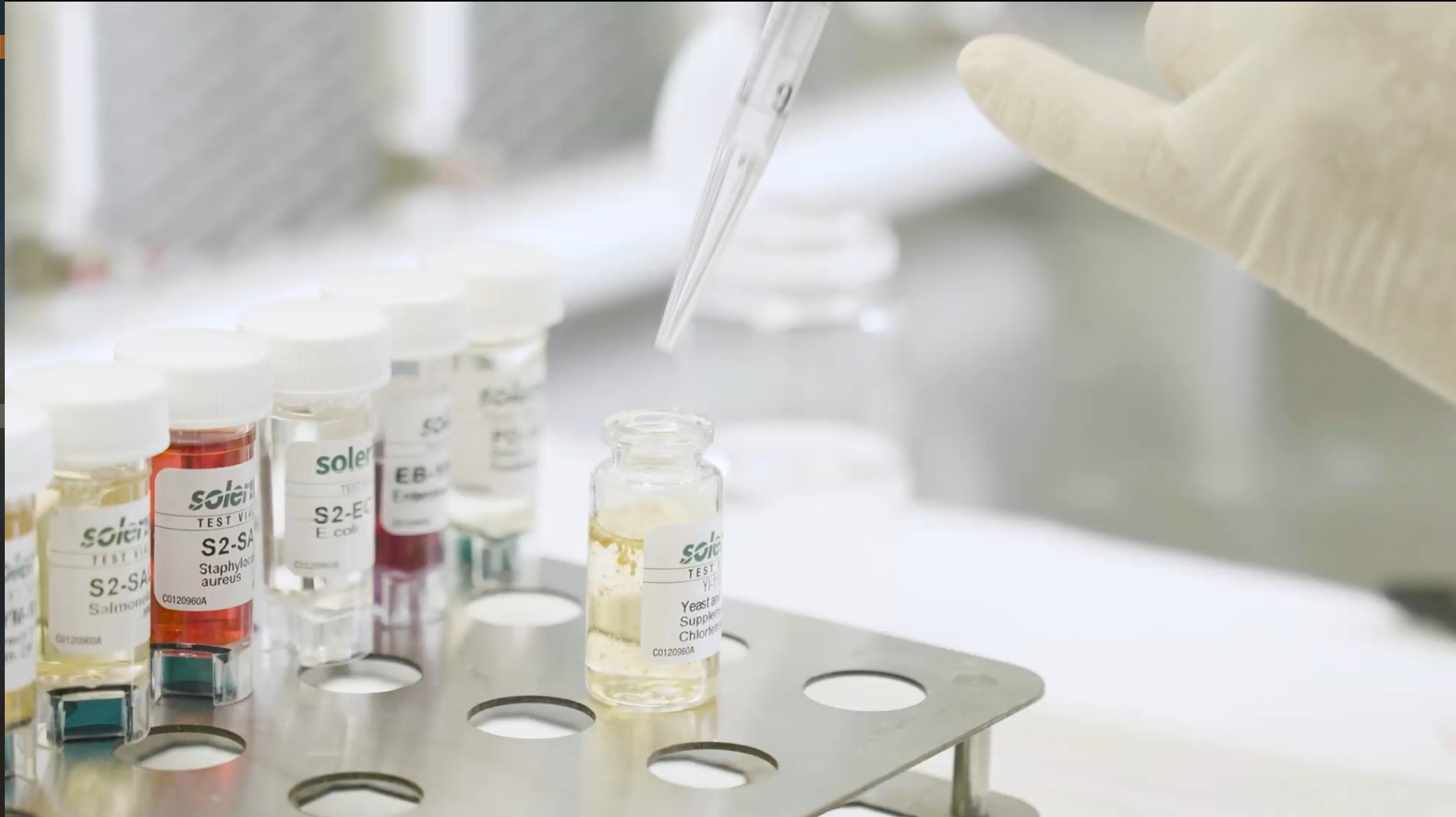 Lab technician pipetting a supplement sample into a test vial, representing the testing steps from formula brief to batch record.